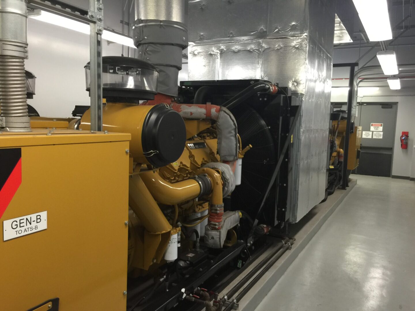 Yellow heavy equipment with cylindrical tubes attached to a wall-sized ventilation fan