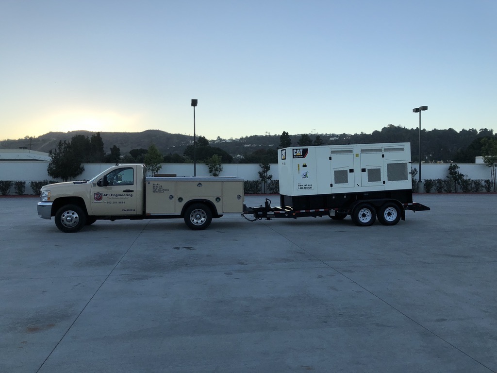 Cream-colored pickup truck towing a white CAT generator