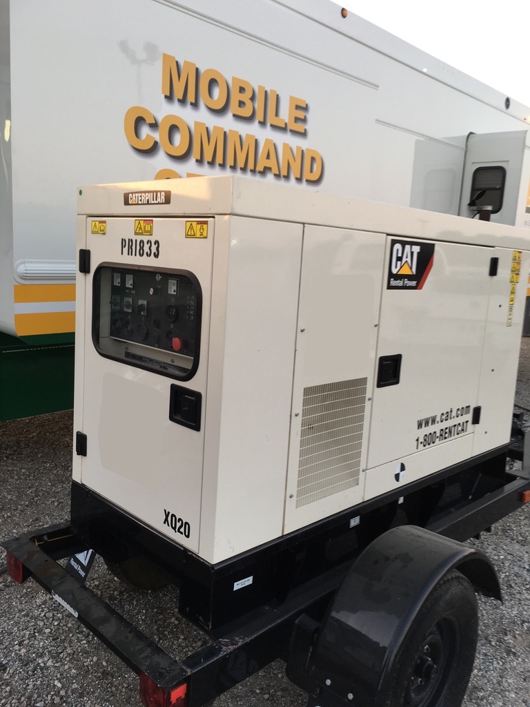 Cream-colored CAT generator next to a mobile command vehicle