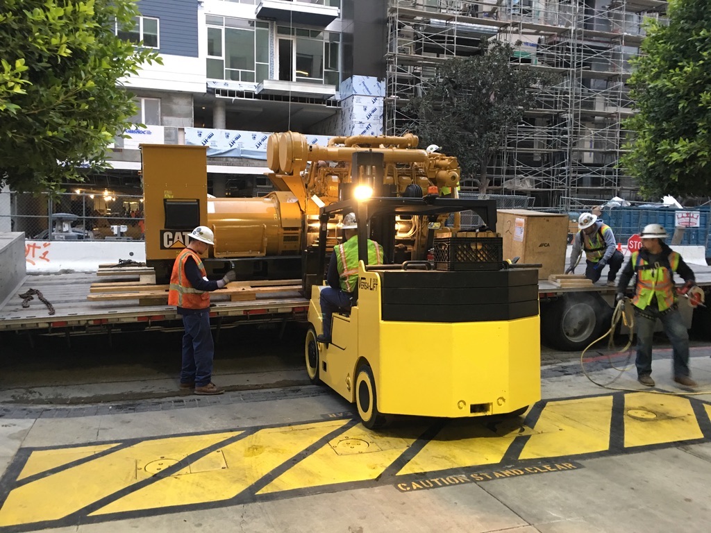Forklift carrying a platform containing a big yellow CAT generator attachment