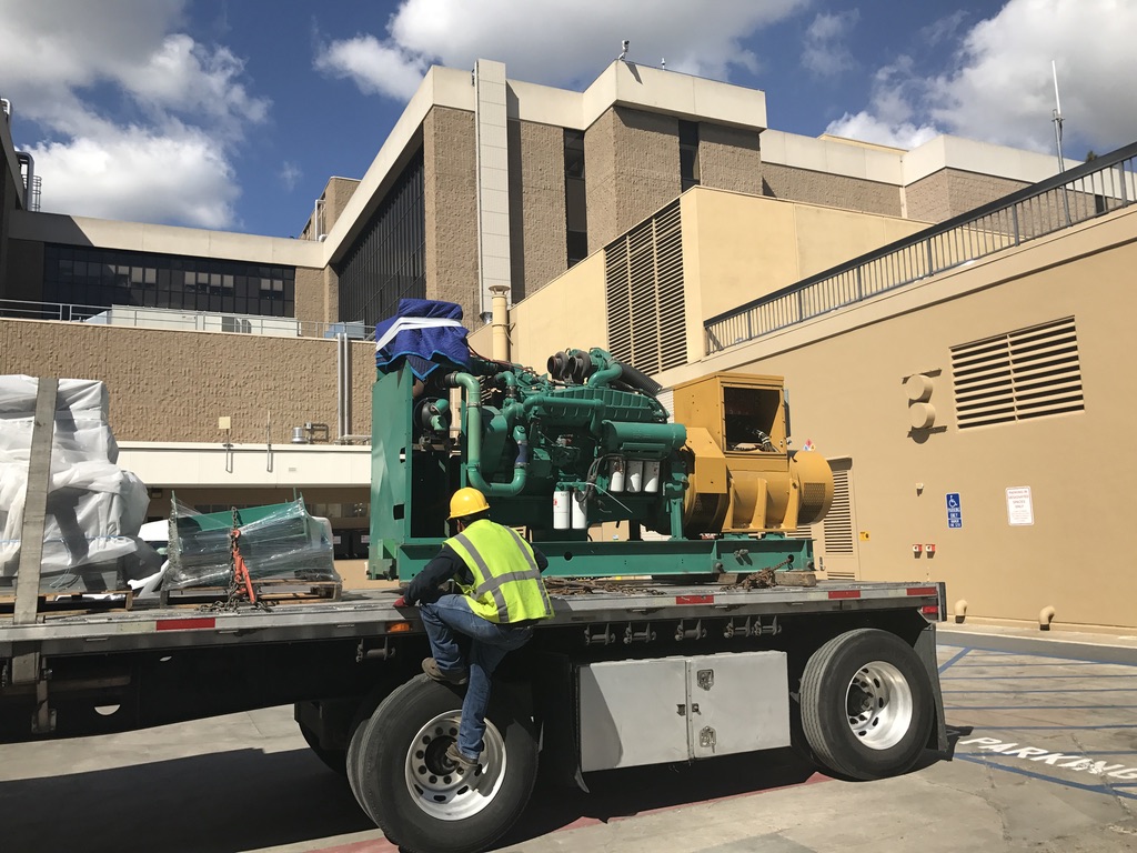 Blue-green generator attachment loaded on a truck’s trailer platform