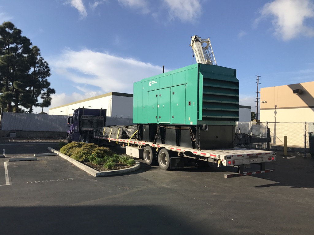 Big blue-green generator equipment on a metal platform attached to a truck