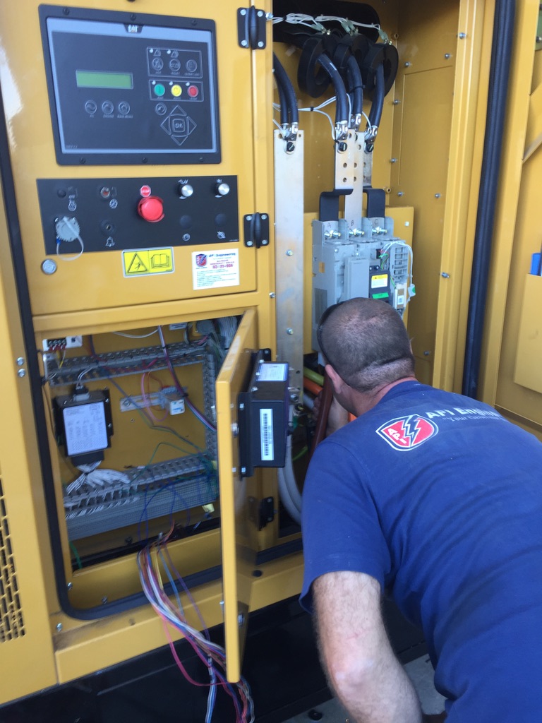 Guy in a black shirt inspecting the control panel of an opened yellow generator