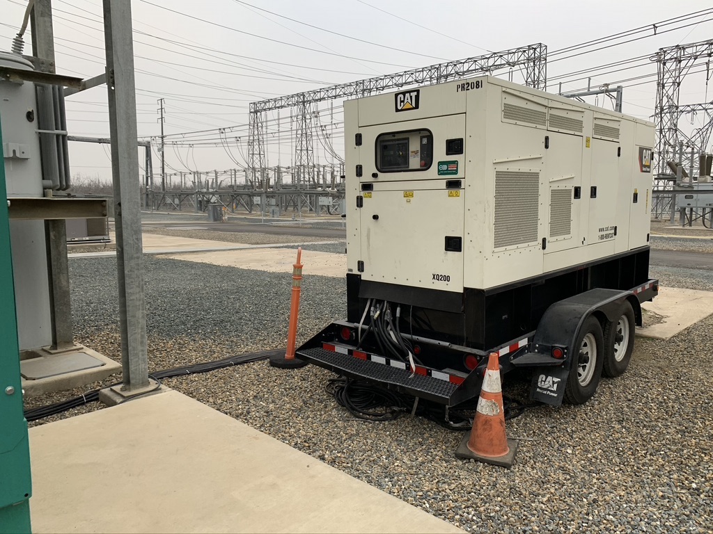 Light beige CAT generator parked near a sidewalk