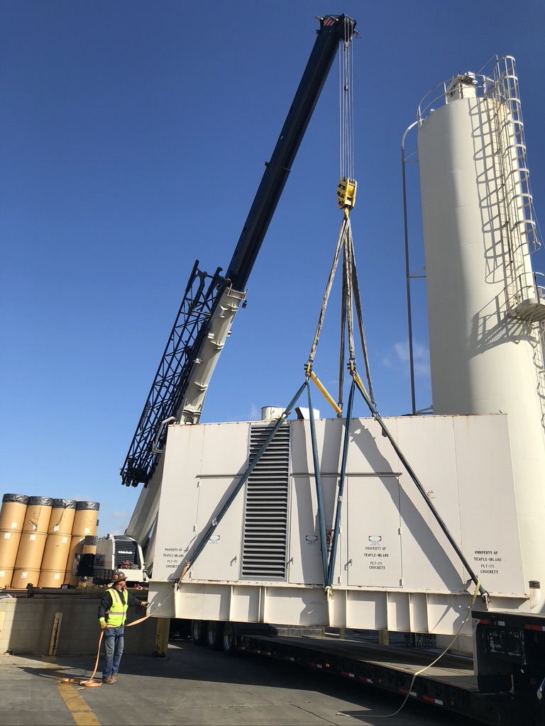 White rig truck lifting up a huge white generator next to a white round tower