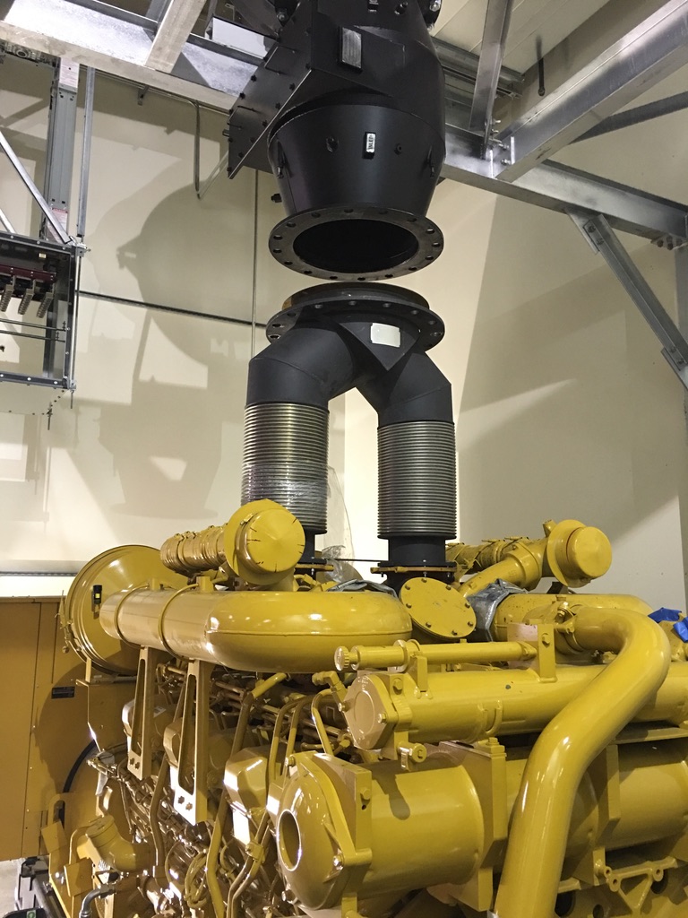 Black ventilation ducts above cylindrical tubes of a yellow generator