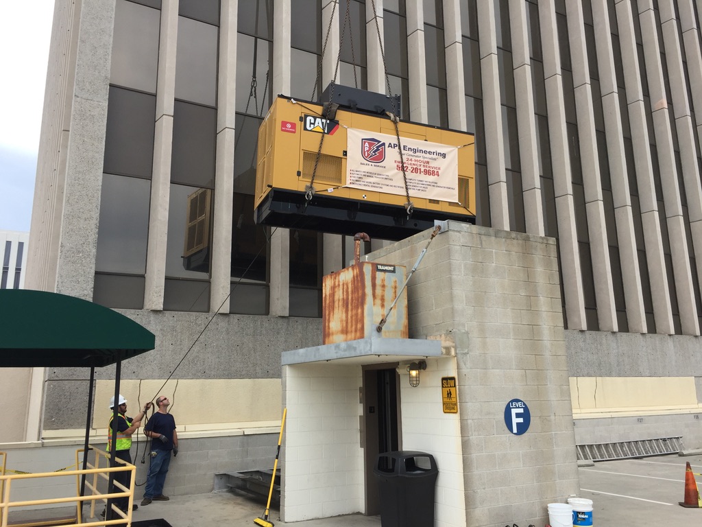 Yellow CAT generator being lifted above a roofless building