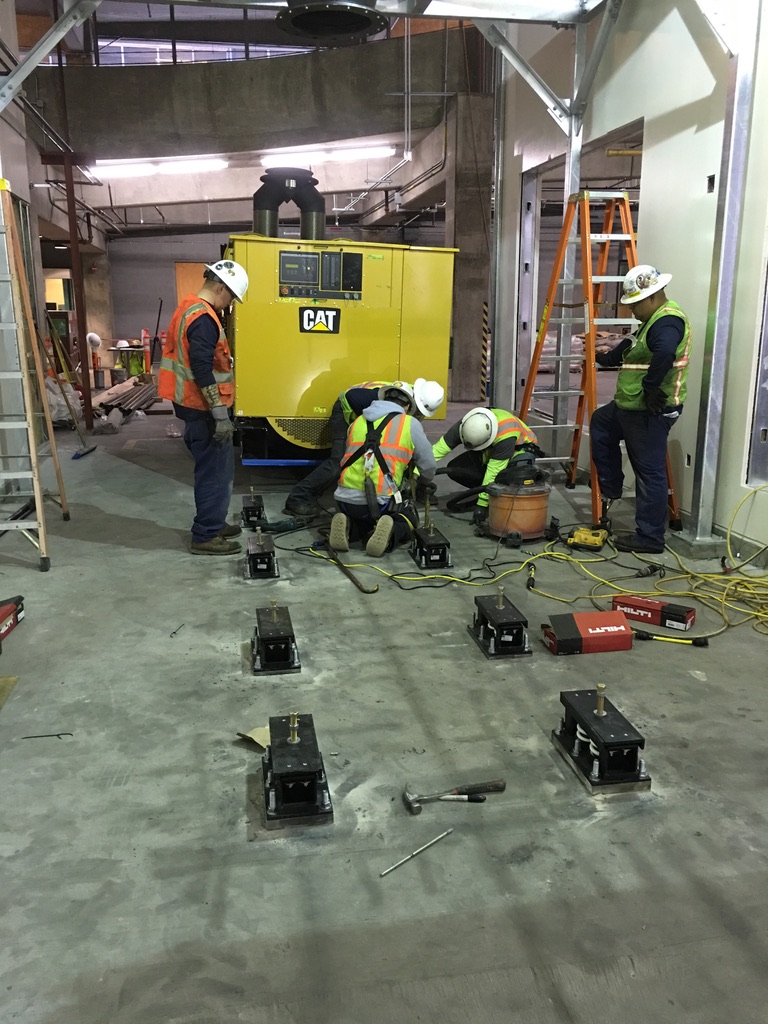 Men in hazard jackets installing protective equipment for holding generator units in place