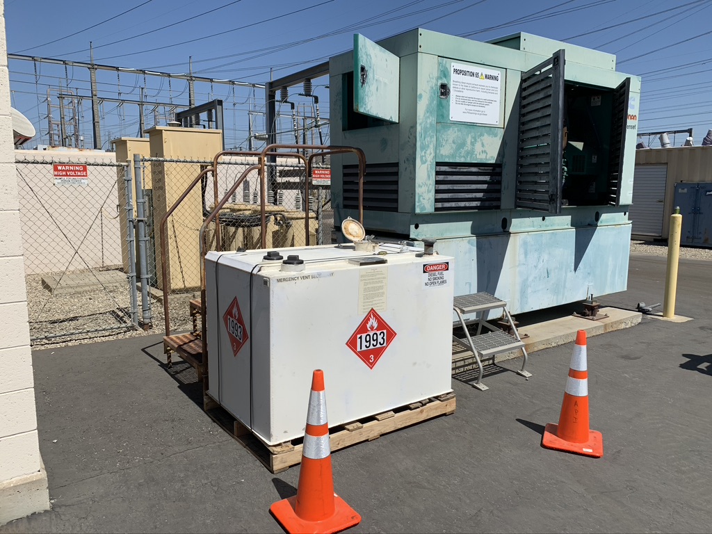 Faded blue-green generator housing next to supplementary generator equipment outdoors
