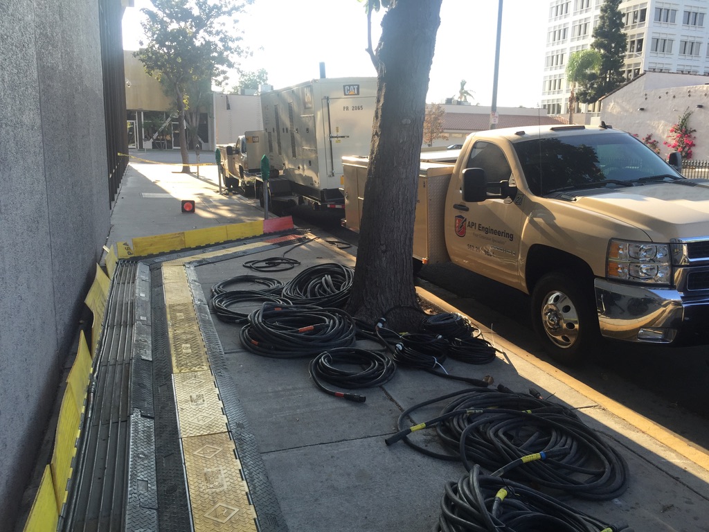 Bundles of generator cable surrounding a tree next to a parked cream-colored pickup truck