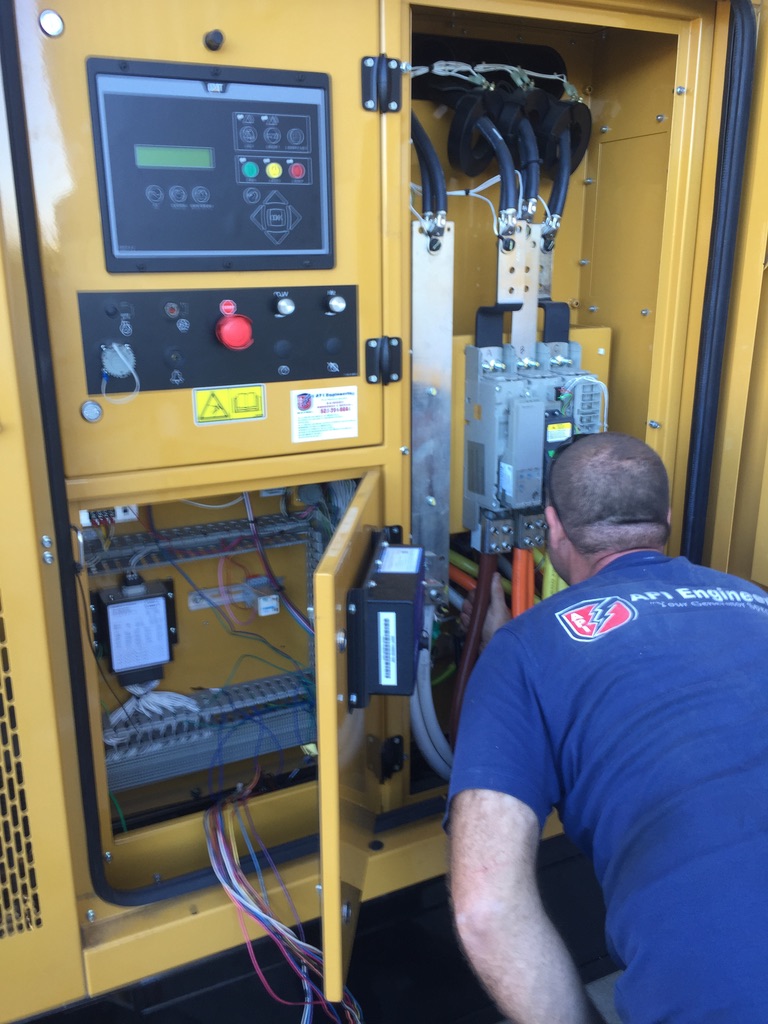 Guy in a black shirt inspecting the control panel of a yellow generator