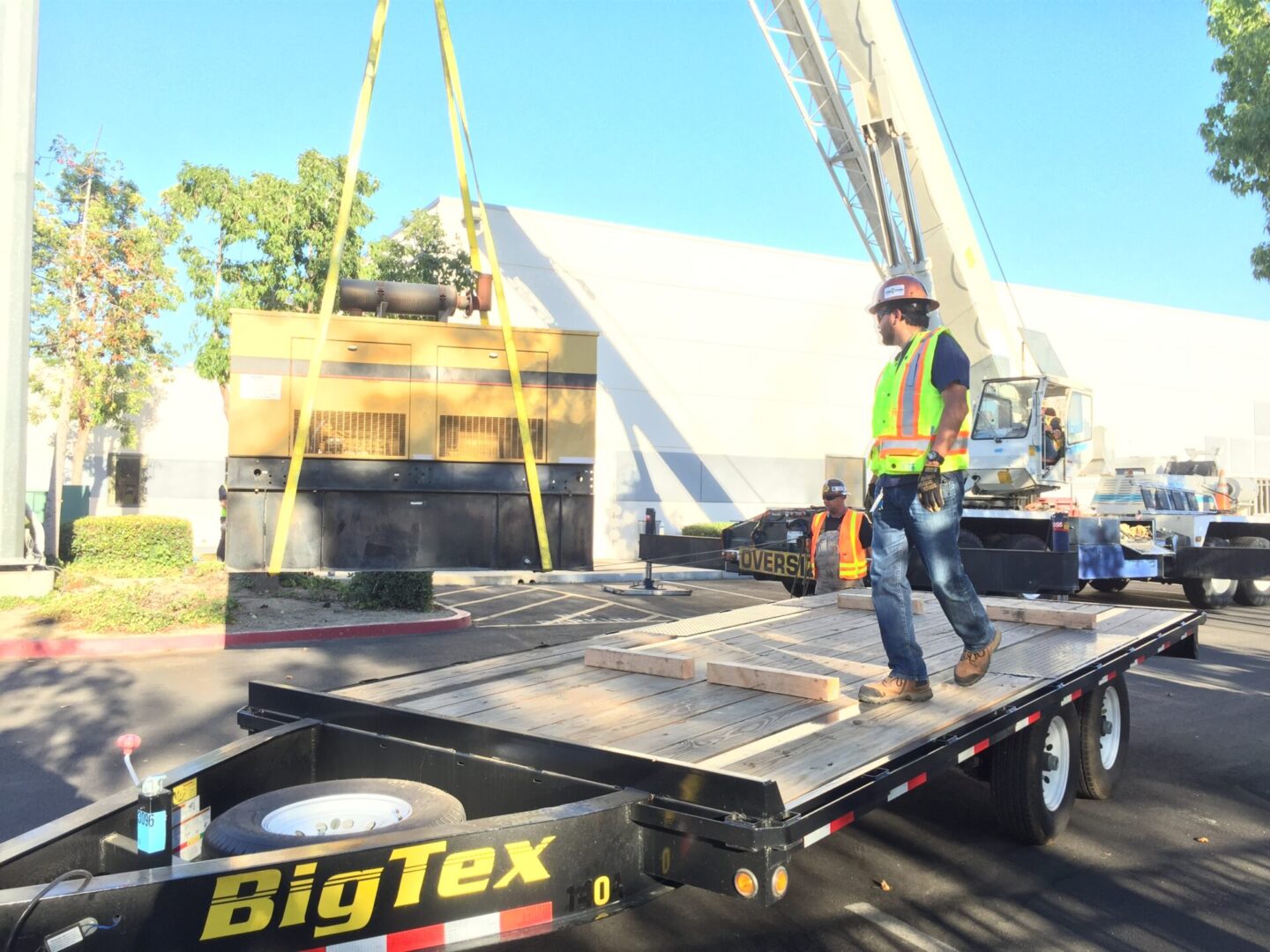 Big yellow generator being loaded unto a wooden platform using a pulley lift truck